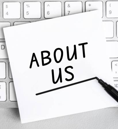 White paper with text About us lying on the keyboard